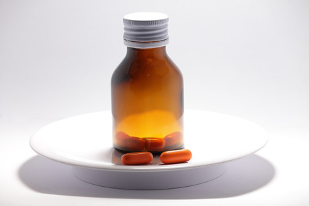 Vitamin pills are outside the bottle on the plateの写真素材