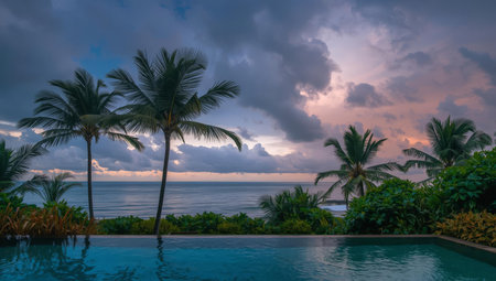 Beautiful view of infinity swimming pool with palm trees at sunset.の素材