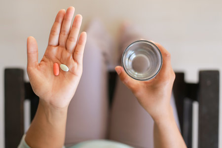 Closeup of female hands holding a glass of water and pills.の写真素材