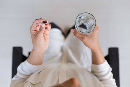 Closeup of a woman holding a glass of water and a pillの写真素材