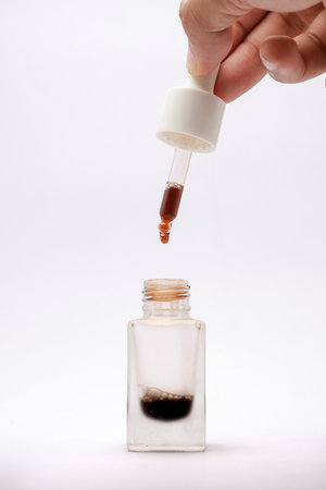 Close-up view of isolated serum in a glass bottle with a white backgroundの写真素材