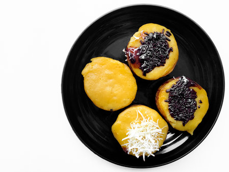 Mini pancakes with black currant jam on a black plate isolated on white backgroundの写真素材