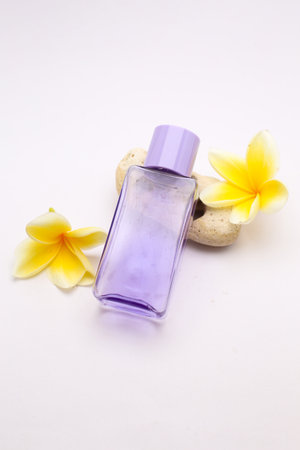 Elegant Perfume Bottle with Yellow Plumeria Flowers on White Background for Spa and Beautyの写真素材