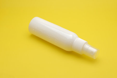 Isolated White Spray Bottle Against a Bright Yellow Background.の写真素材