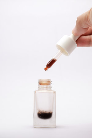 Close-up view of isolated serum in a glass bottle with a white backgroundの写真素材