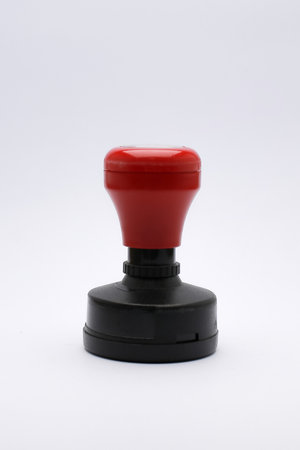 Red and Black Rubber Stamp on White Surface Close-Up. showcasing its compact design and functionality.の写真素材