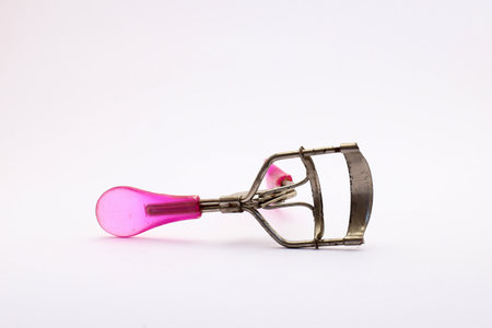 Pink and Silver Eyelash Curler on White Background for Makeup Use. an essential beauty tool for curling eyelashes, enhancing the natural look.の写真素材