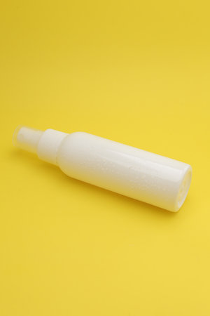 Isolated White Spray Bottle Against a Bright Yellow Background.の写真素材