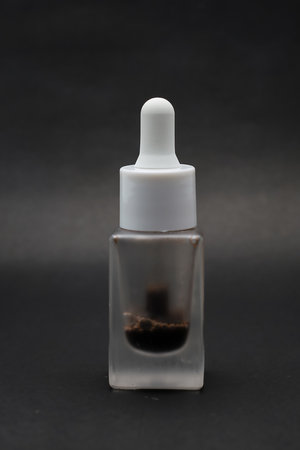 Close-up view of isolated serum in a glass bottle with a Black backgroundの写真素材