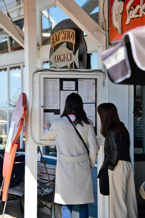 Travelers looking at a lunch menu.  On a sunny April day, two tourists look at the posted lunch menu...