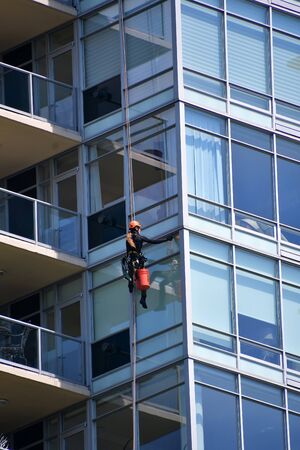 A window washer cleaning the window of a high rise building. Vancouver BC Canada June. 25th 2019...