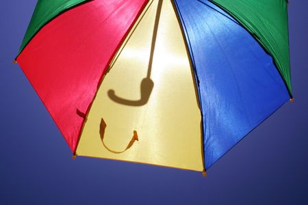 flying multicolored umbrella on clear blue skyの写真素材