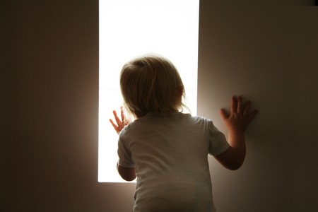 little baby is looking out of the windowの写真素材