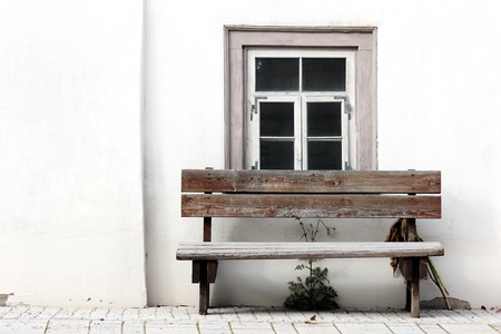 old bench in front of an weathered window with white wallの写真素材