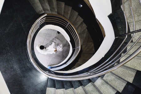Two lovely couple dance from the top in the center of spiral staircase