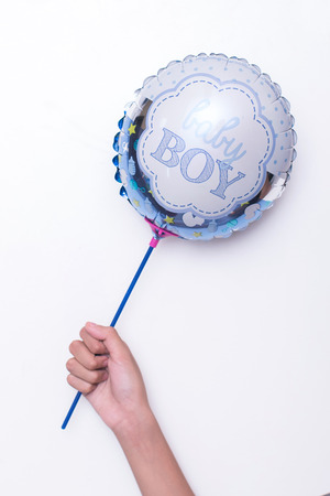Blue and white balloon written baby boy hold by kid's hand on white backgroundの写真素材