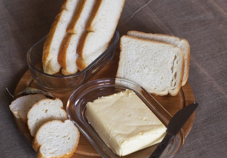 On the table, white bread with butter.の写真素材