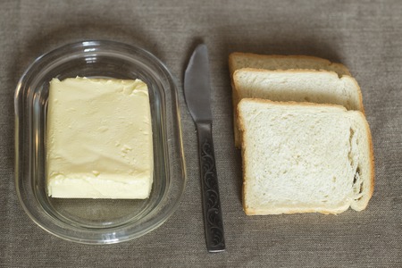 On the table, white bread with butter.の写真素材