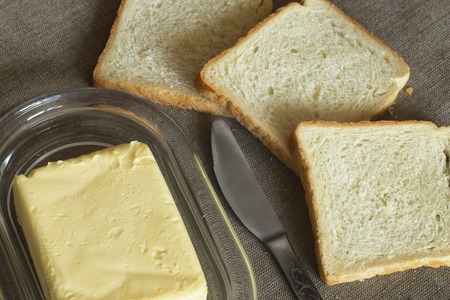 On the table, white bread with butter.