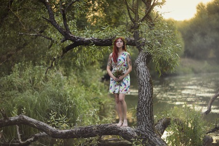 Bright girl with red hair. With a bouquet of berries and leaves on his head. The girl with a tattoo nature.の写真素材