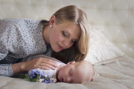 Young woman gently pressed looks at the sleeping baby