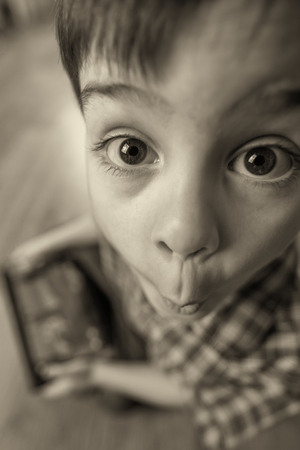 The boy with the tablet was very surprised at what he saw. Strong surprise. Optical distortion of the picture.の写真素材