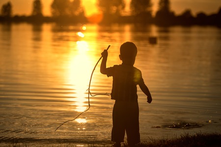 Child at sunset near the pond. Backlightの写真素材