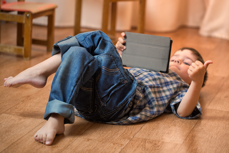 The boy with the tablet was very surprised at what he saw. Strong surprise. Optical distortion of the picture.の写真素材