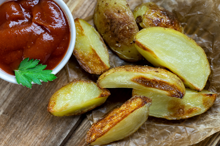 Baked potatoes with ketchup and greensの写真素材