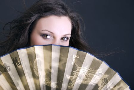 Portrait of a young beautiful brunette with fan close-upの写真素材