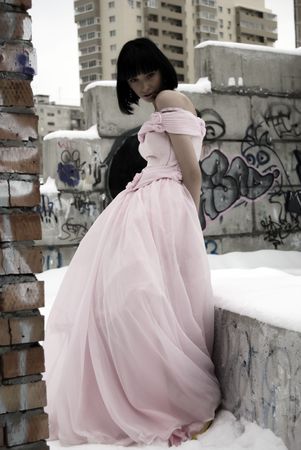 young bride in pink wedding dress standing among street ruinsの写真素材