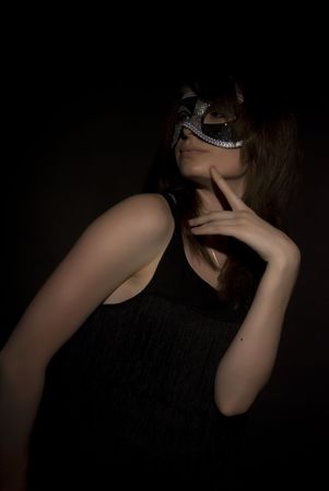 Portrait of a young brunette in mask over blackの写真素材