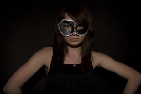 Portrait of a young brunette in mask over blackの写真素材