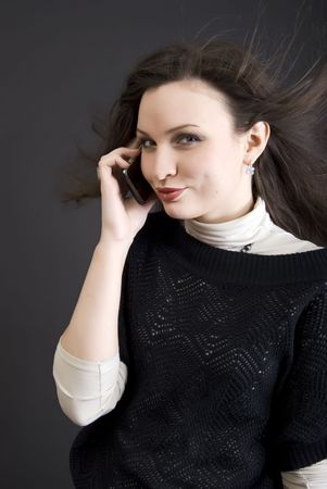 Portrait of a young beautiful brunette talking by the cell phoneの写真素材