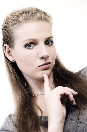 Portrait of a young beautiful girl with her forefinger on the chinの写真素材