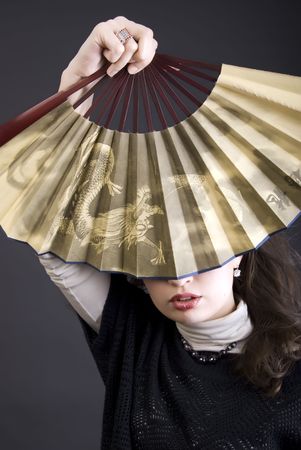 Portrait of a young beautiful brunette posing with fan の写真素材