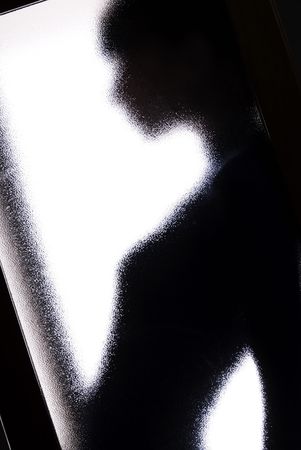 black silhouette behind the glass as a concept of depression and lonelinessの写真素材