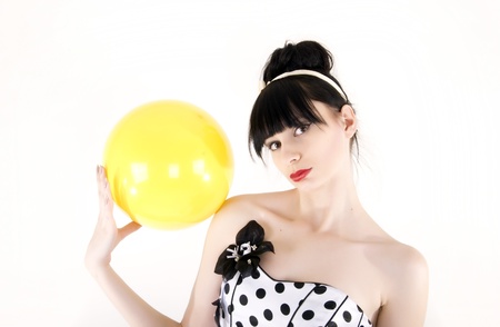 Portrait of a young beautiful brunette posing with yellow ballの写真素材