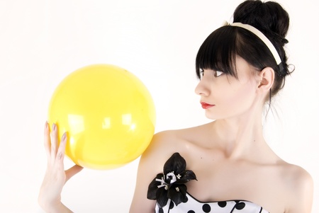Portrait of a young beautiful brunette posing with yellow ballの写真素材