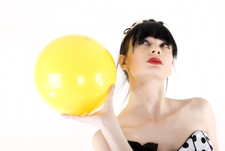 Portrait of a young beautiful brunette posing with yellow ballの写真素材