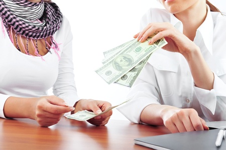 Portrait of two young pretty women in an offive environment. One gives money to another. Credit conceptの写真素材
