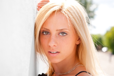 Portrait of pretty young woman standing outdoors near white wallの写真素材