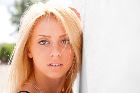 Portrait of pretty young woman standing outdoors near white wallの写真素材