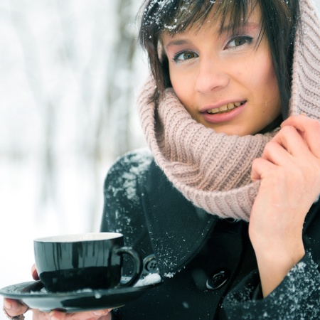 Portrait of young beautiful woman standing alone in winter park and drinking coffee. Take-away coffee as natural as it can be - concept. Advertisement bannerの写真素材