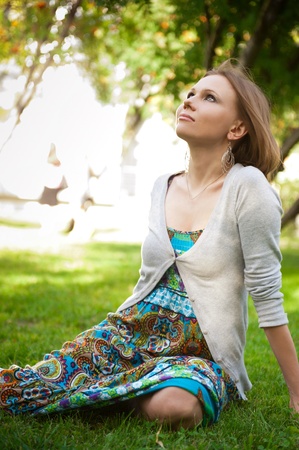 Full length of pretty young woman resting on grass and smiling. Touching her hairの写真素材