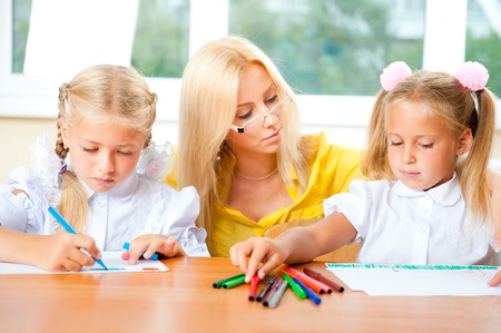 Young pretty teacher helping to her students to make exercise indoors at classroom. Horizontal Shotの写真素材