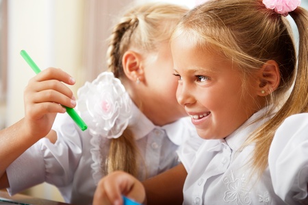 Two little girls gossip in classroomの写真素材
