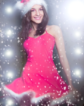 20-25 years od beautiful woman in christmas dress dancing at club while celebrating christmas party. Snowflakes flying around herの写真素材