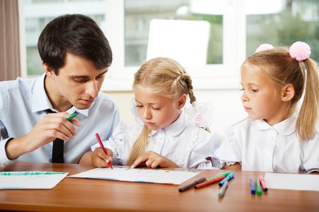 Teacher helping students with schoolwork in school classroom. Horizontally framed shot.の写真素材