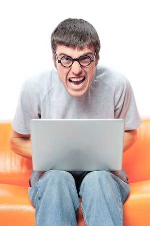 Closeup portrait of funny handsome young relaxing man using laptop and sitting on the sofa, wearing round glasses. の写真素材